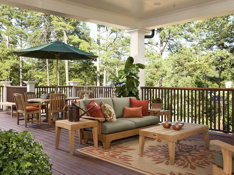Spacious wooden deck with natural teak furniture, dining area, and lush pine tree forest backdrop
